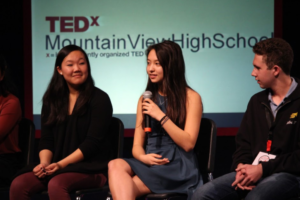 Naya Chang, Katherine Shok, and Zachary Hinz address the audience during the student 
