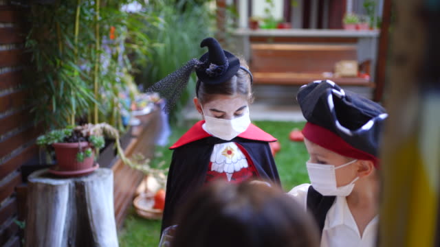 Group of kids trick or treating during Covid-19 pandemic wearing face masks